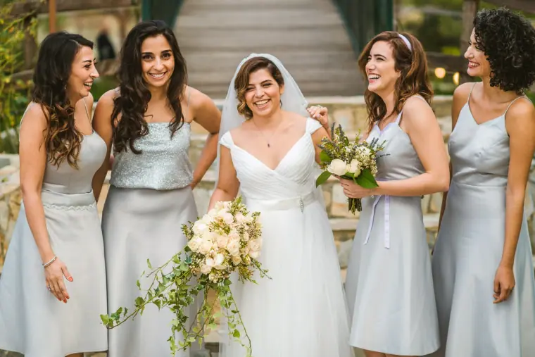 Bride laughing with her bridesmaids in pale grey satin dresses