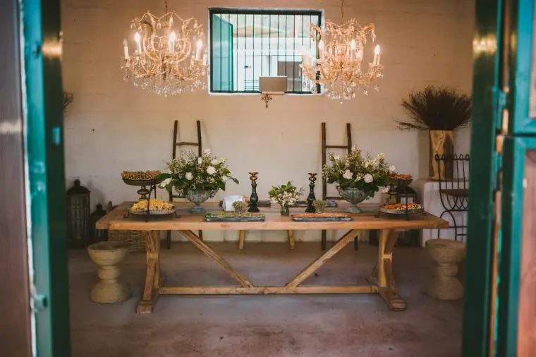 Grazing table beneath crystal chandeliers in a whitewashed barn at Lexeko Estate