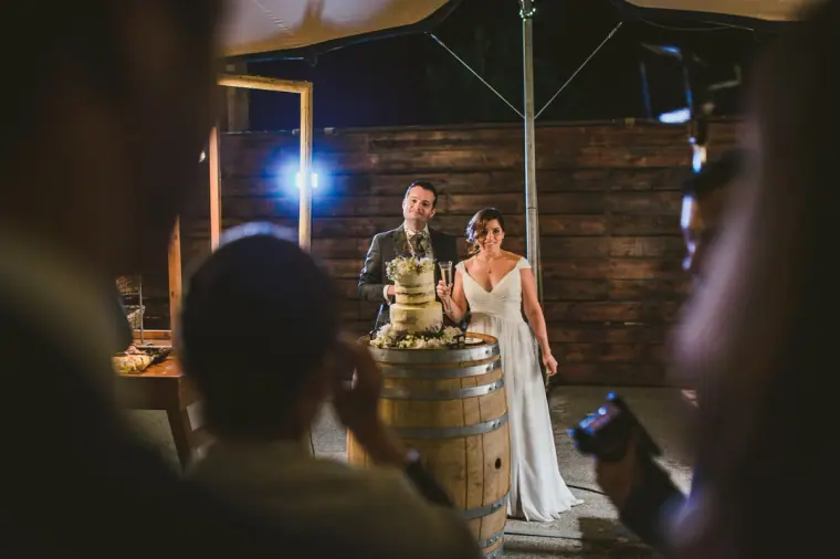 Guests photographing the couple at the cake on a wine barrel