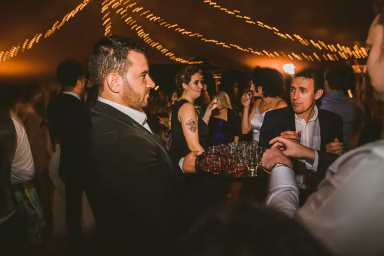 Guests crowding around a tray of shots at the evening reception