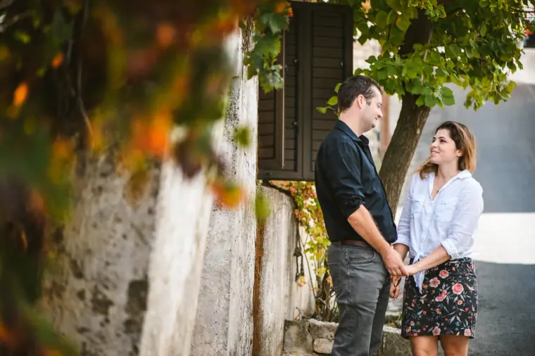Nermine and Christopher holding hands by an old stone house in Lefkara, Cyprus