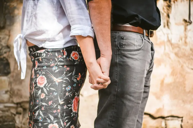 Close-up of the couple's linked hands, her floral trousers beside his jeans