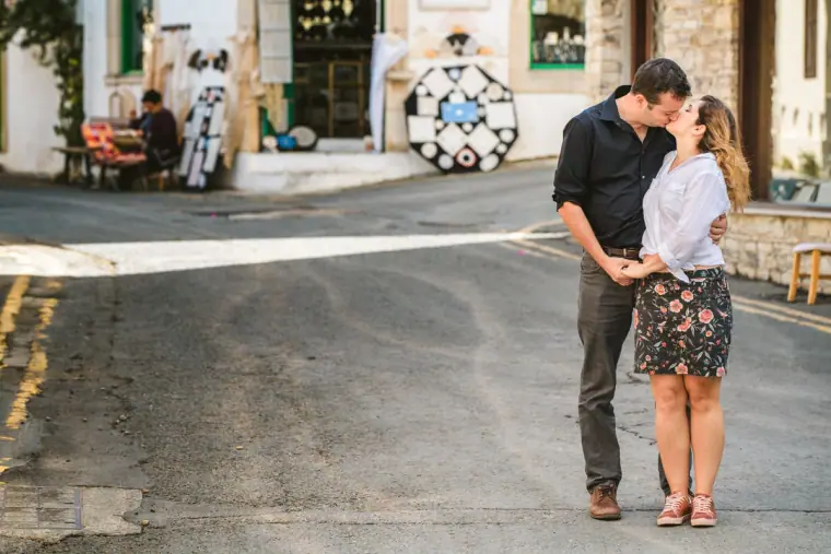 Couple kissing in a village street with a lace shop behind them in Lefkara