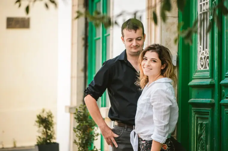 Couple posing arm in arm beside an ornate green door