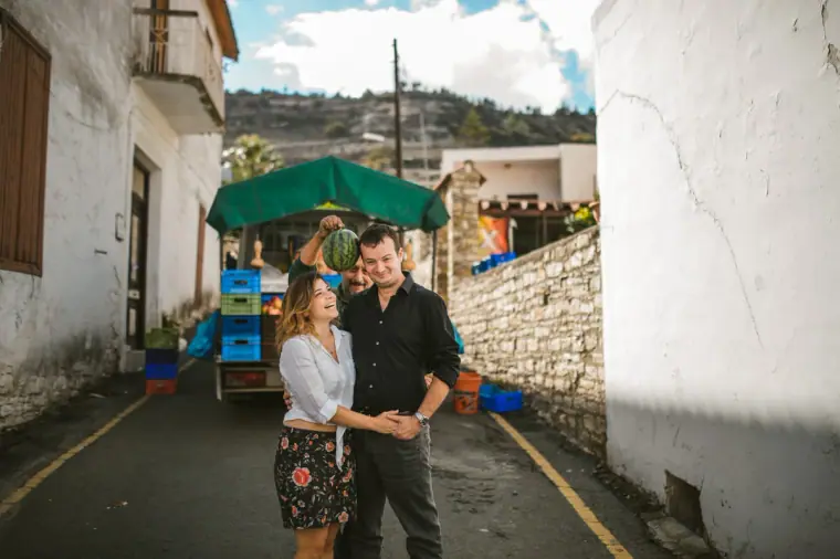 Couple embracing in a narrow lane as a market stall passes behind them