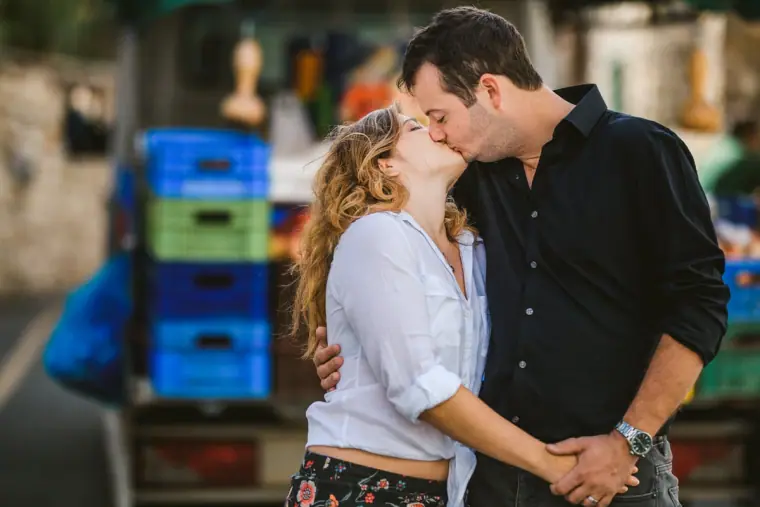 Couple kissing beside stacked blue crates at a village shop