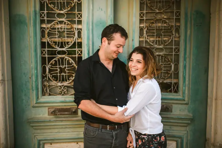 Nermine and Christopher embracing in front of a turquoise wrought-iron door in Lefkara