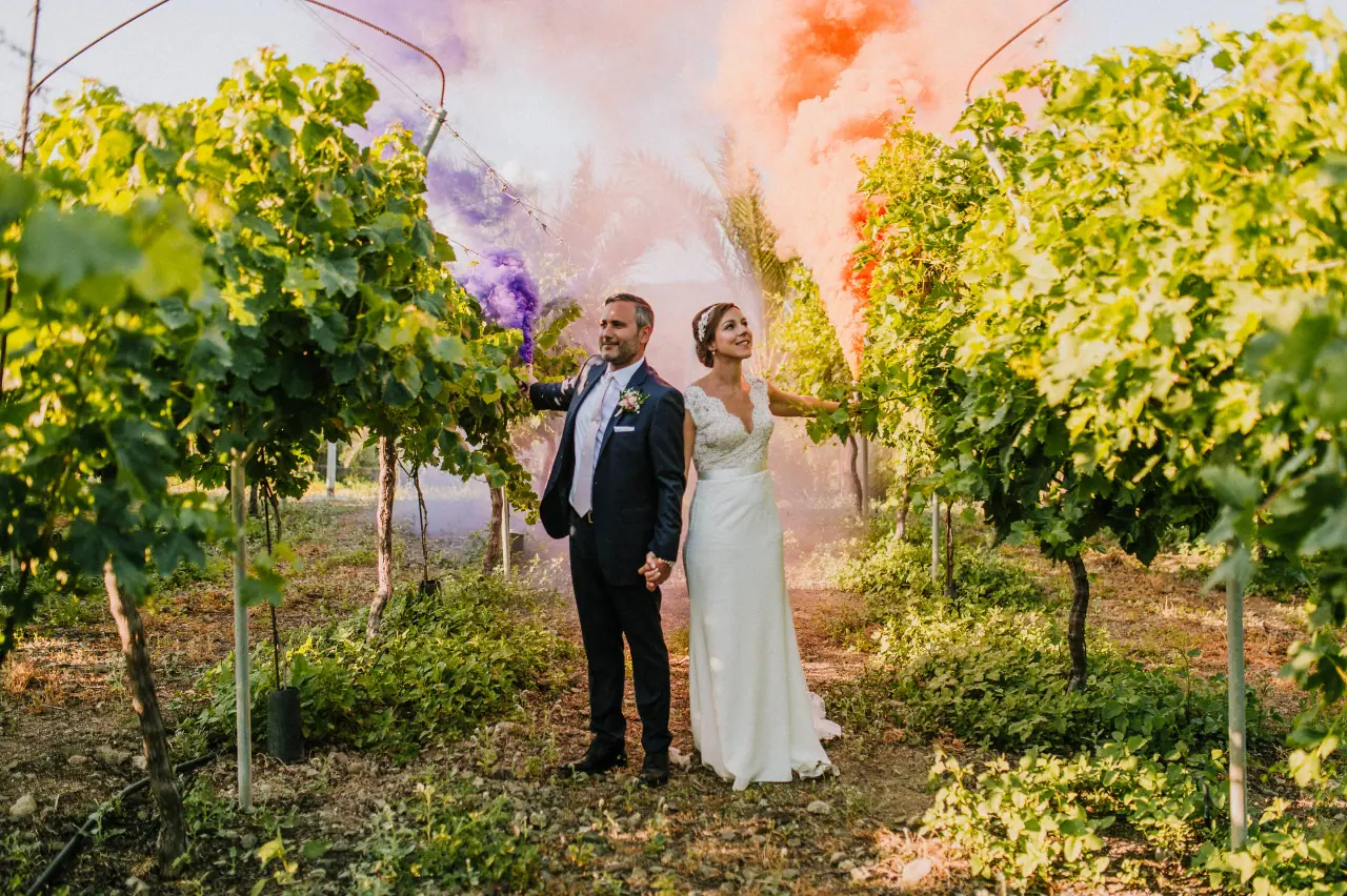 Stacey and Chris among vineyard rows as coloured smoke drifts behind them at Hadjiantonas Winery, Limassol