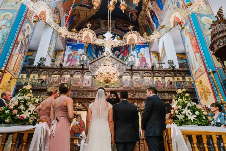 Greek Orthodox ceremony before a gilded iconostasis and frescoed walls near Limassol, bridesmaids in blush pink
