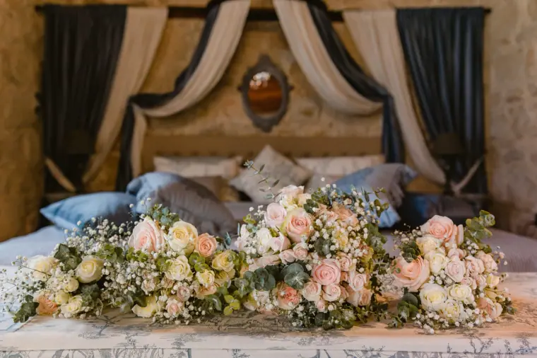 Pastel rose and gypsophila bouquets laid on a canopy bed in a stone-walled room