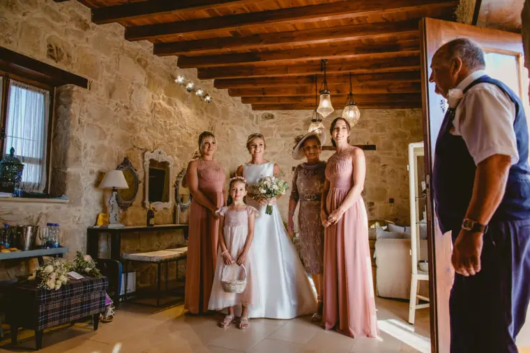 Bride's father seeing her for the first time as bridesmaids and flower girl look on