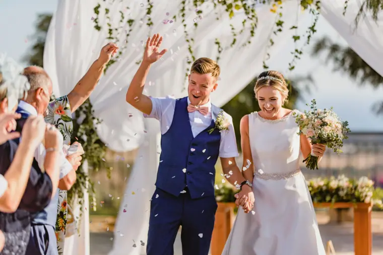 Groom raising his arms in celebration as the couple walk back down the aisle