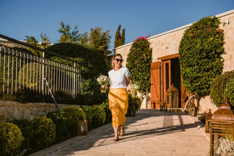 Guest in a yellow skirt walking along a stone path lined with bougainvillea