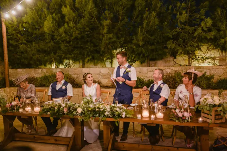 Wide view of the top table with guests and flowers during the speeches