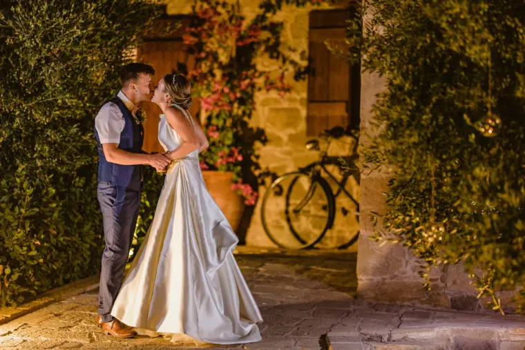 Couple embracing in a stone courtyard by an old bicycle and bougainvillea