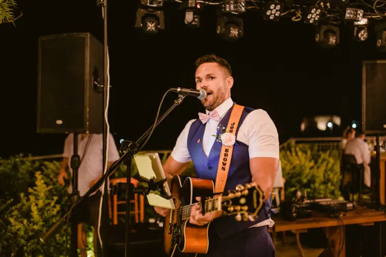 Singer with an acoustic guitar performing on stage at night