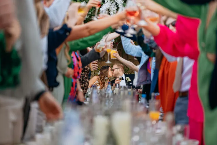 Guests raising glasses of fizz in a toast, seen past a tray of drinks