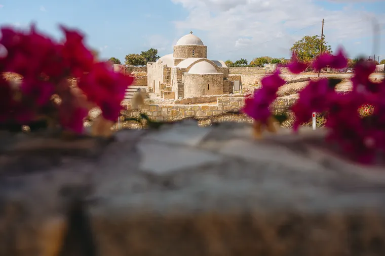 Domed stone church seen past pink bougainvillea in Kouklia, Paphos