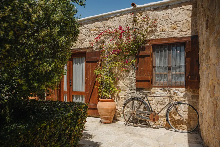 Stone cottage with wooden shutters, bougainvillea and a vintage bicycle at Liopetro