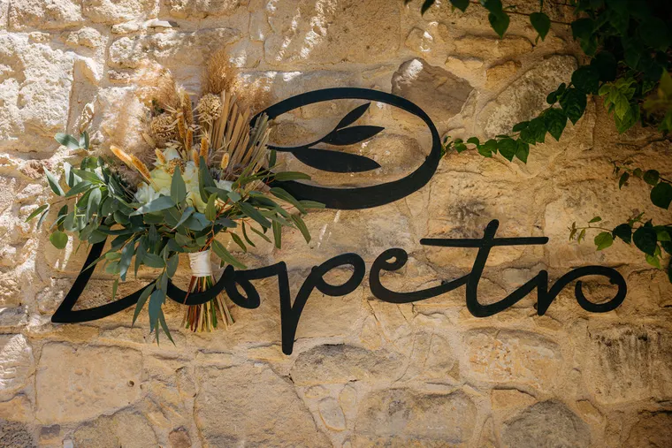 Liopetro sign on a stone wall decorated with a dried flower and pampas bouquet