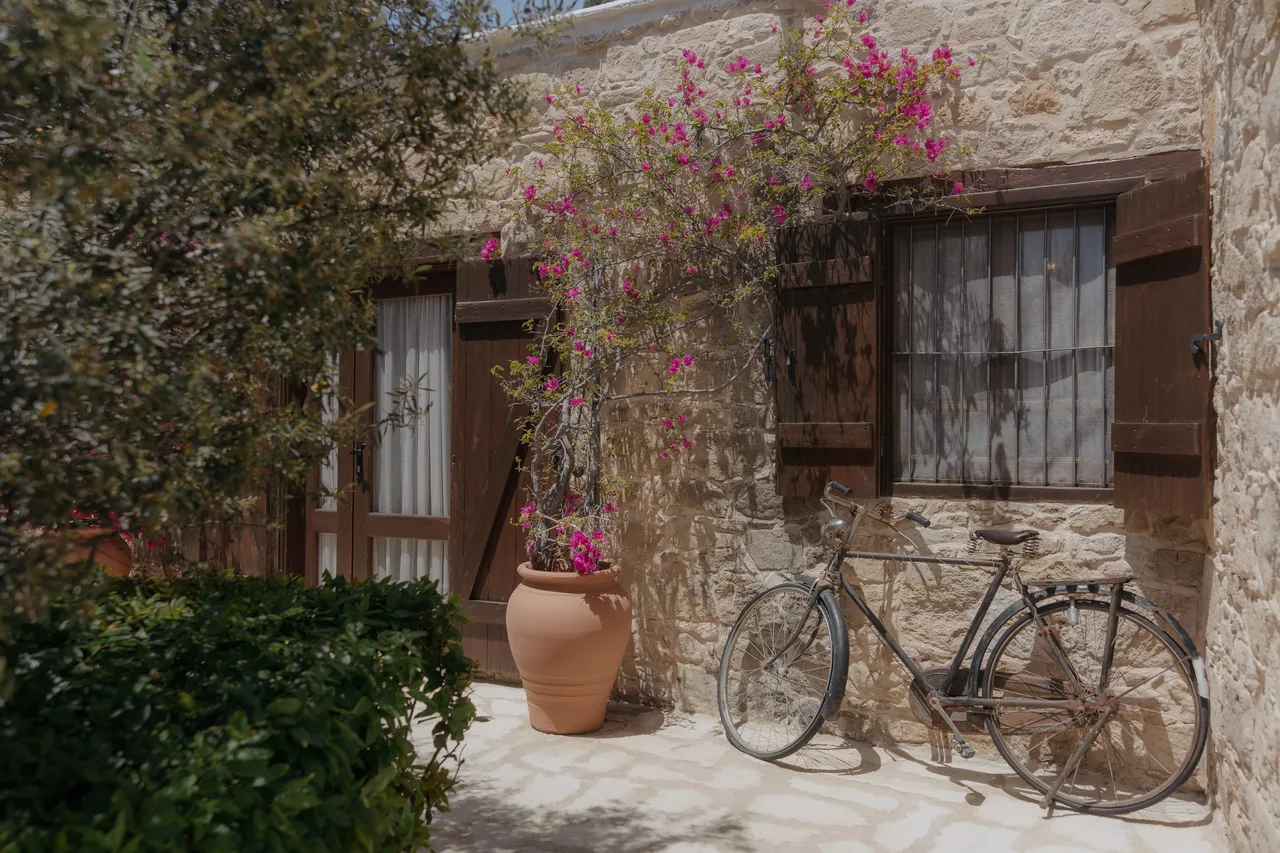Vintage bicycle against a stone cottage with bougainvillea and wooden shutters at Liopetro