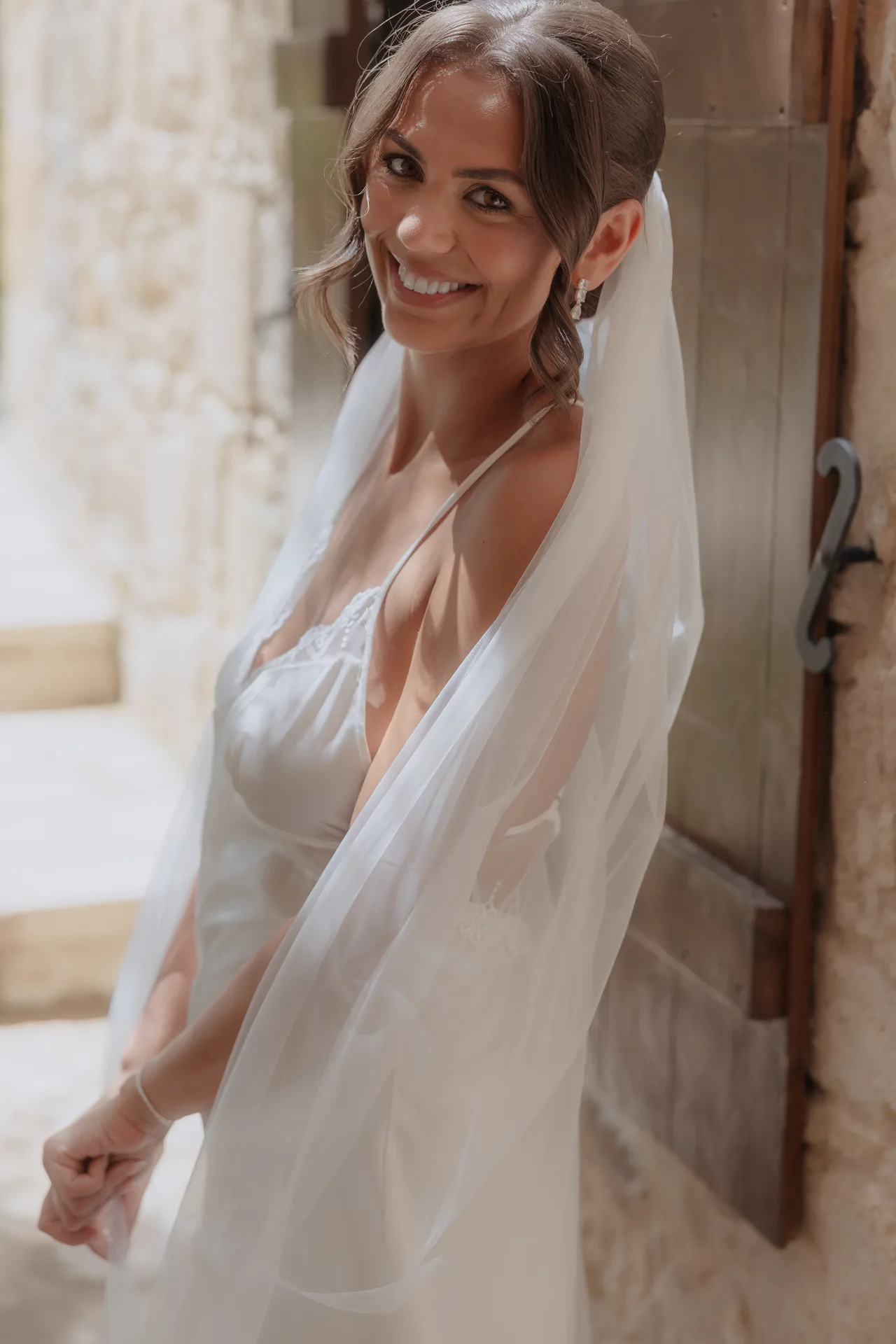 Bride glancing back over her shoulder in a sunlit stone doorway at Liopetro, Kouklia