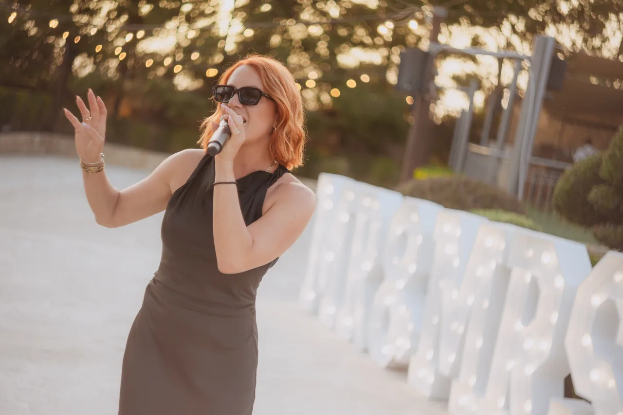 Singer performing beside illuminated MRS letters at the reception at Liopetro, Kouklia