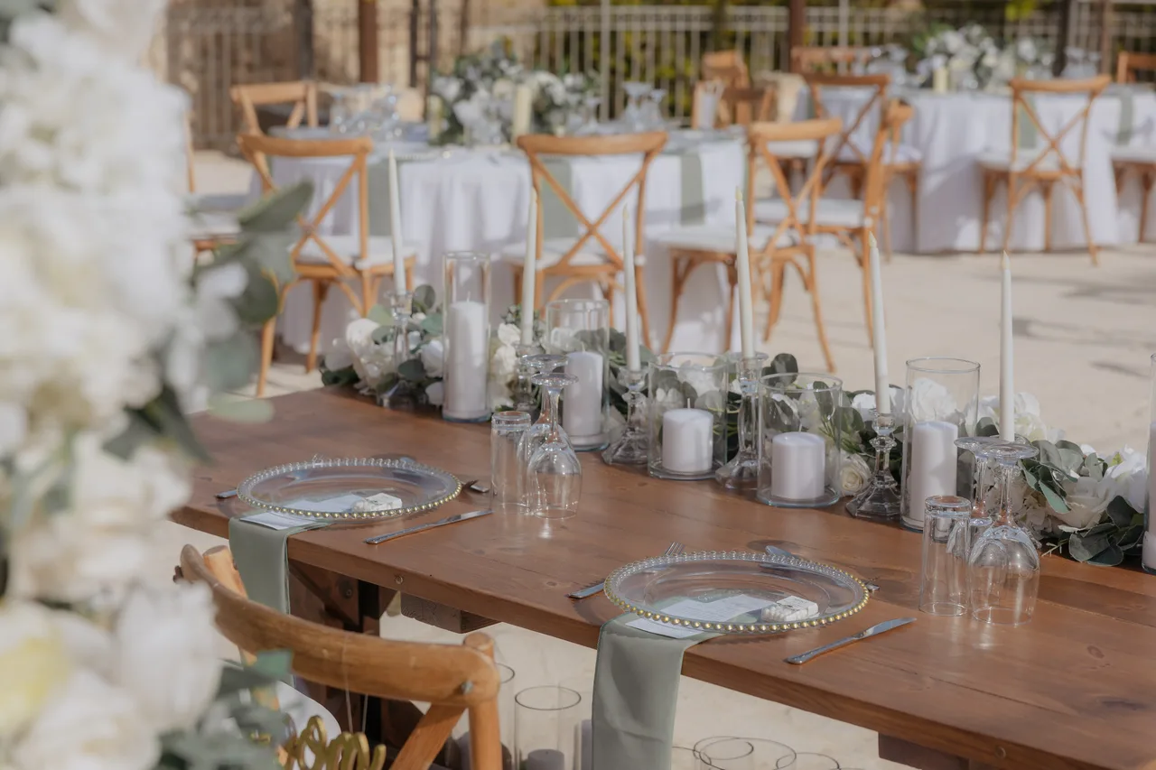 Long table with candles, white flowers and sage napkins set for the wedding breakfast