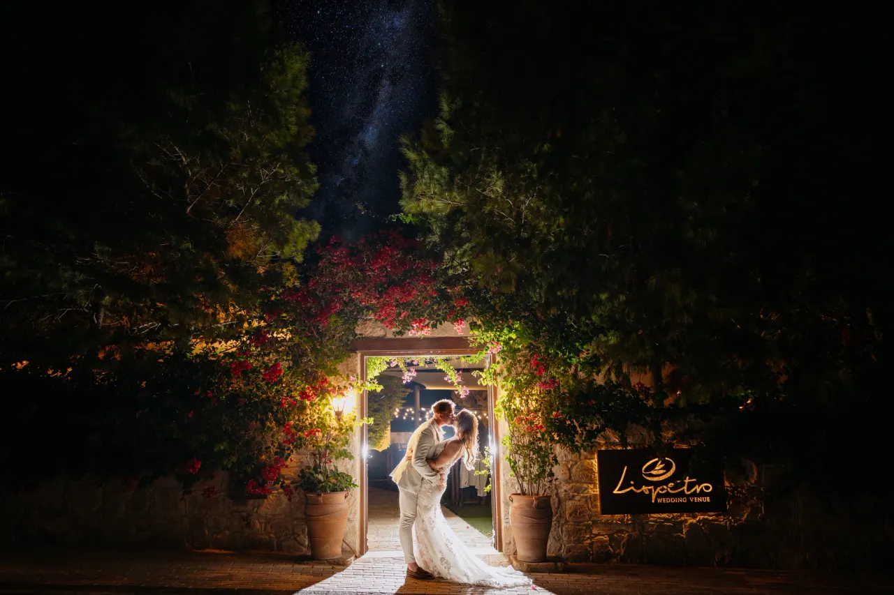 Bride and groom kissing beneath a starlit sky at Liopetro's bougainvillea-framed entrance, Kouklia