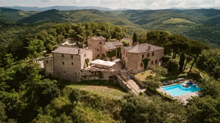 Aerial view of the stone hamlet and swimming pool of Livernano Estate in the Tuscan hills