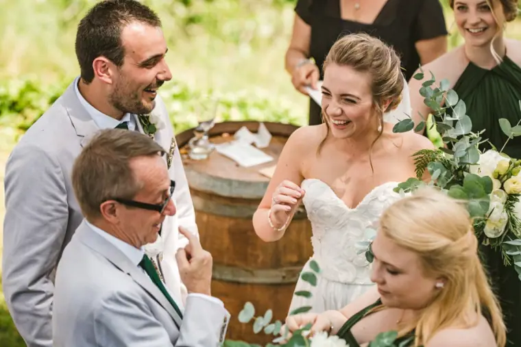 Bride laughing with her bridesmaids as the groom and best man look on during the ceremony