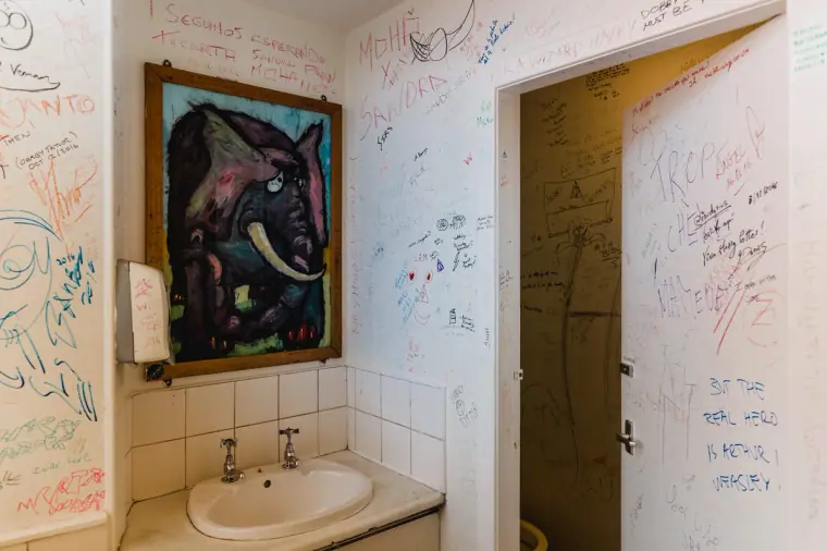 Washroom at The Elephant House café covered in handwritten graffiti, with an elephant painting