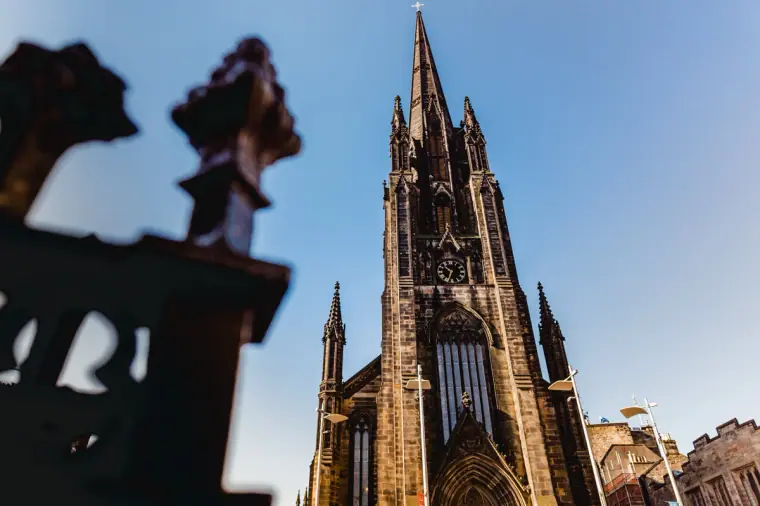 Tall Gothic church spire rising against a deep blue sky in Edinburgh