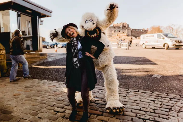 Woman posing with a furry white monster costume performer on the castle esplanade