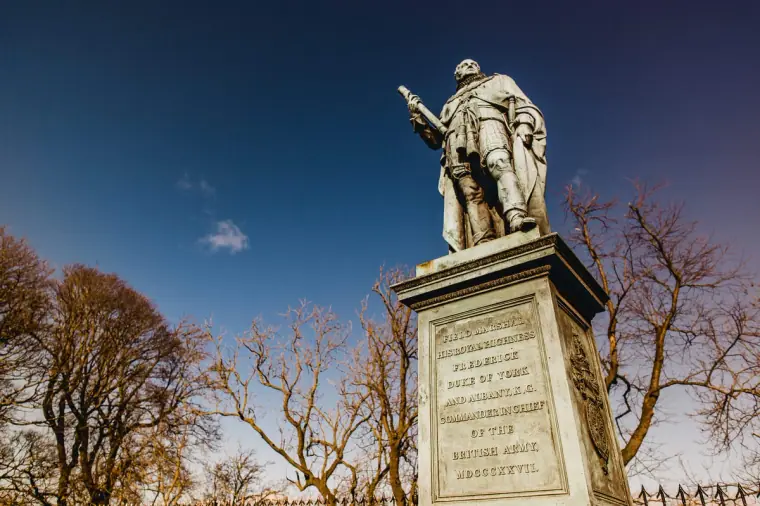Statue on a tall stone plinth beneath bare trees and blue sky, Edinburgh
