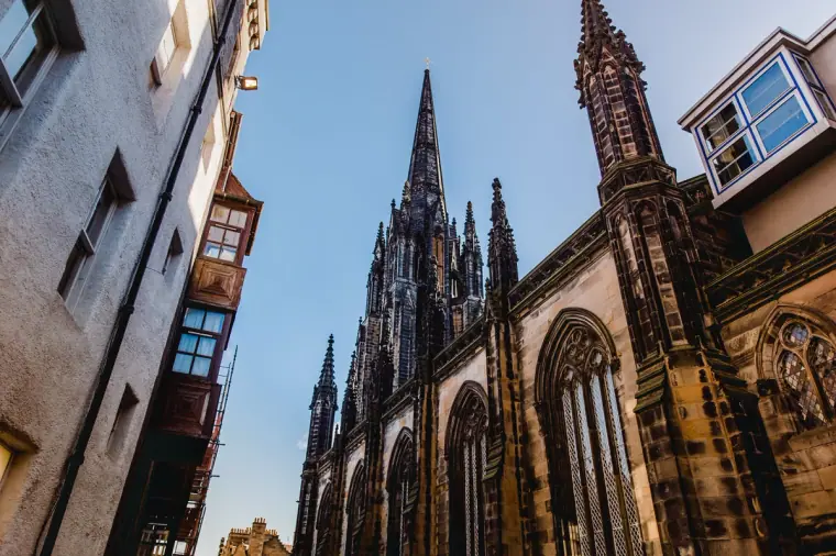 Gothic spires of an Edinburgh church looming over old Royal Mile buildings