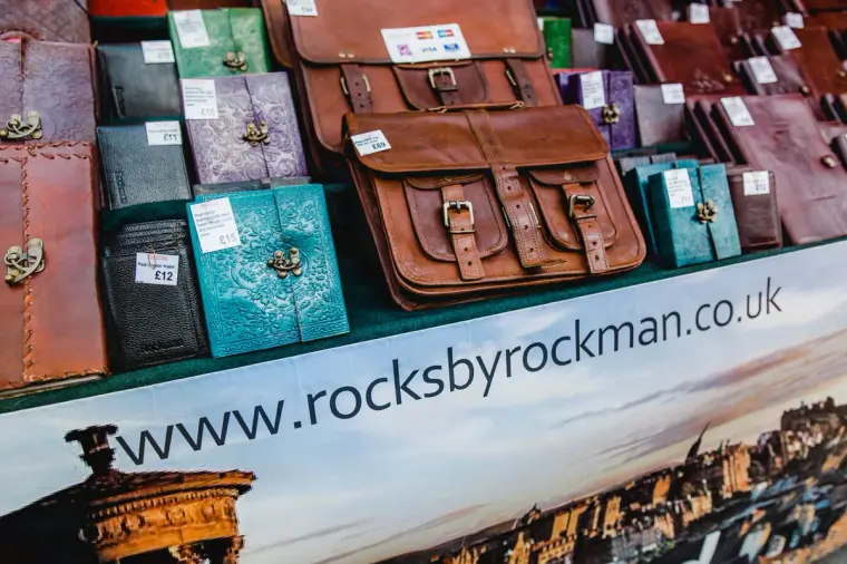 Leather satchels and colourful notebooks on a market stall with a rocksbyrockman sign
