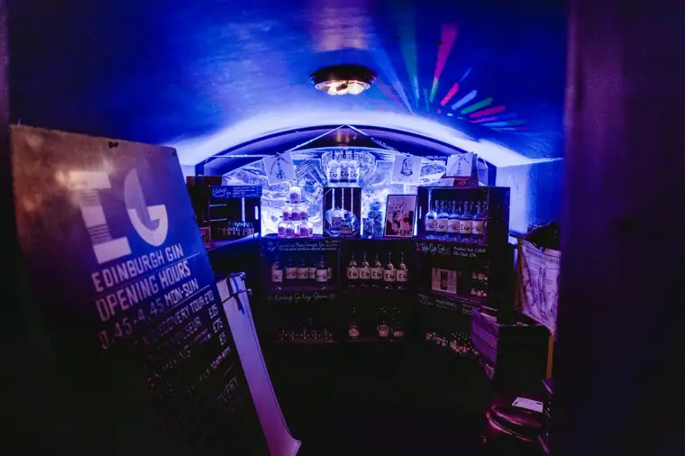 Edinburgh Gin sign in a blue-lit vaulted bar lined with bottles