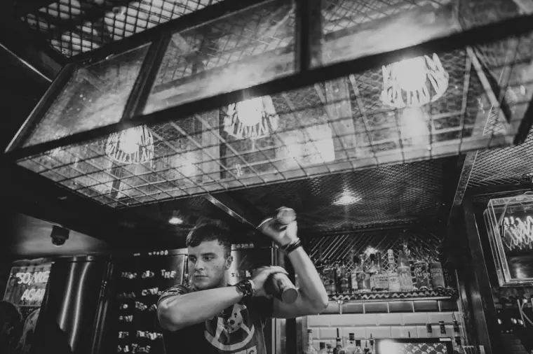 Black-and-white shot of a bartender mid-flair with a cocktail shaker