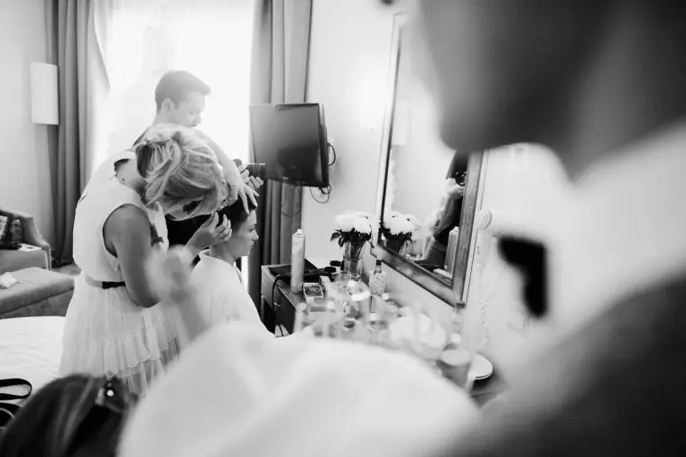 Black-and-white shot of bridesmaids getting ready in front of a mirror