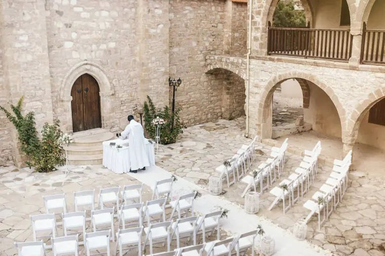Monastery courtyard set with white chairs and a small altar for the ceremony at Minthis Hills