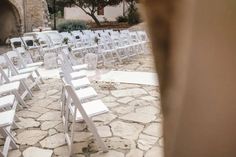 Rows of white folding chairs on the flagstone courtyard ready for the ceremony