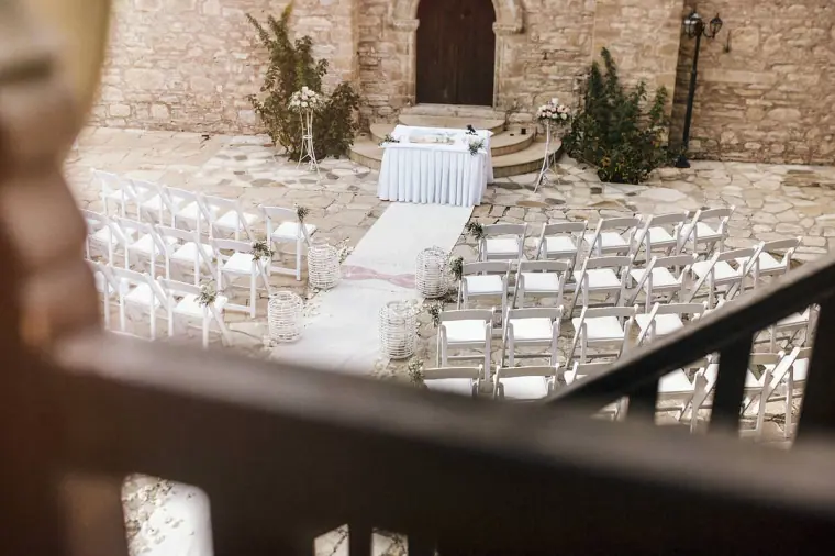 Monastery courtyard with white chairs and an altar table seen from a balcony, Minthis Hills