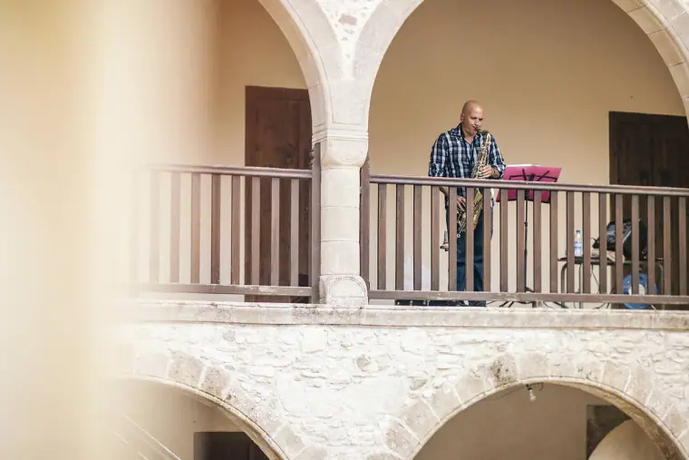 Saxophonist playing on the arched upper balcony of the monastery courtyard