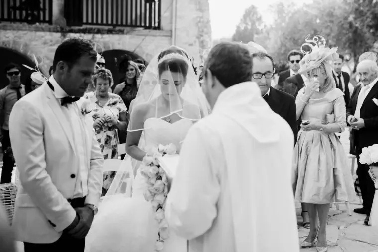 Black-and-white shot of the bride arriving at the altar beside the groom and priest