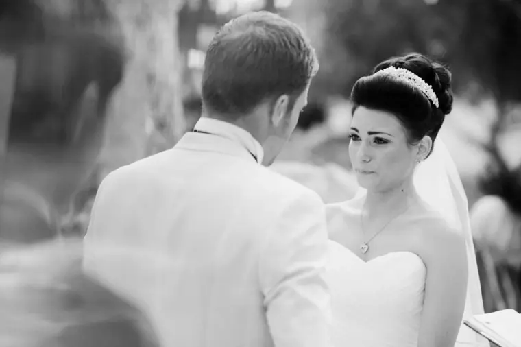 Black-and-white shot of the bride gazing at her groom during the ceremony
