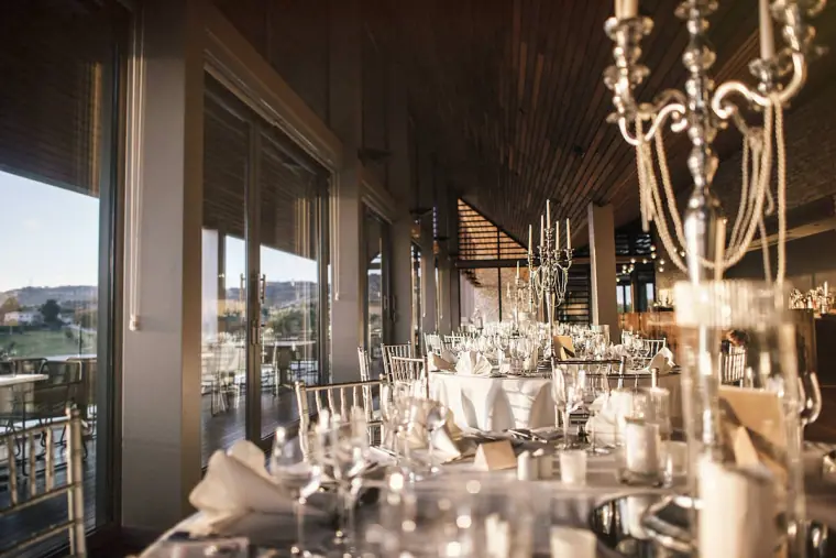 Reception tables with crystal candelabras and glassware by tall windows