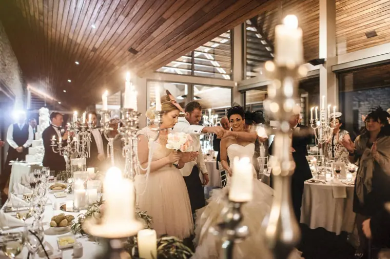 Bride dancing among guests between tall silver candelabras