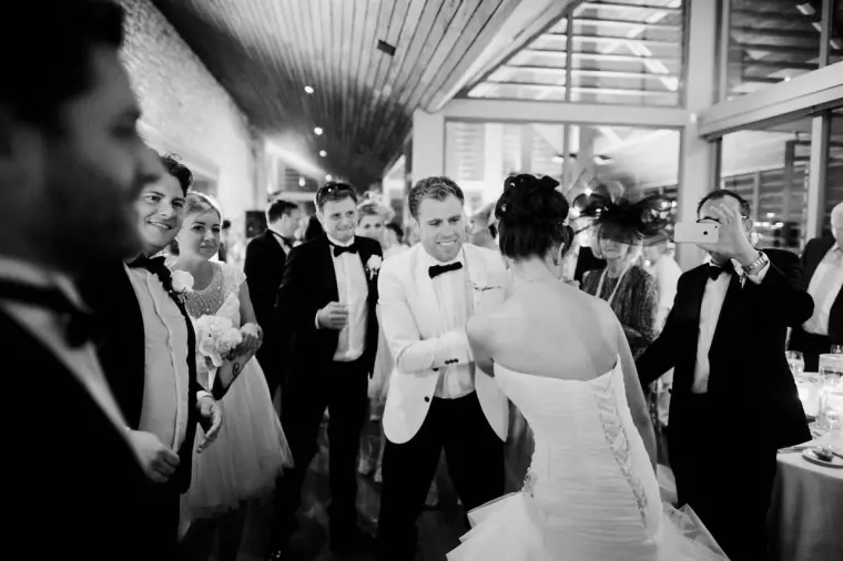 Black-and-white shot of the groom and guests dancing in a circle around the bride