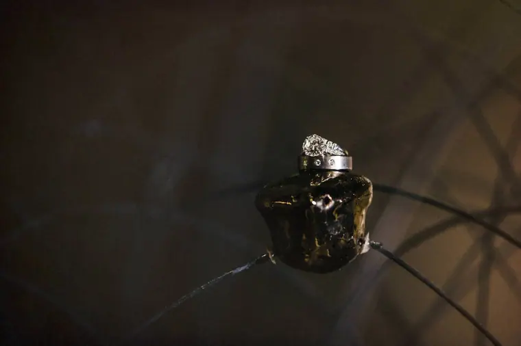 Diamond engagement ring and wedding band resting on a black stone in low light